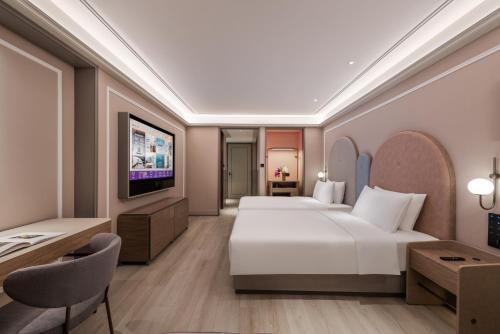 a hotel room with a bed and a television at Mercure Nantong Suxitong Riverside in Nantong