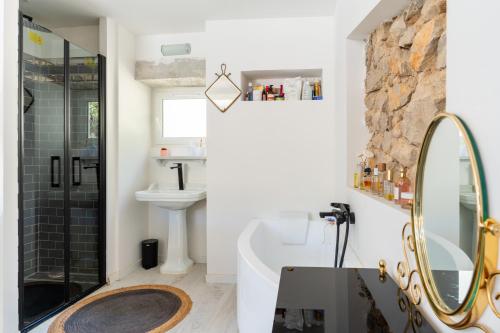 une salle de bain avec une baignoire, un lavabo et un miroir dans l'établissement Maison de charme au coeur des Goudes 5 pers, à Marseille