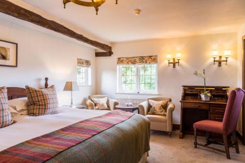 a bedroom with a bed and a desk and chairs at Old Swan & Minster Mill in Minster Lovell