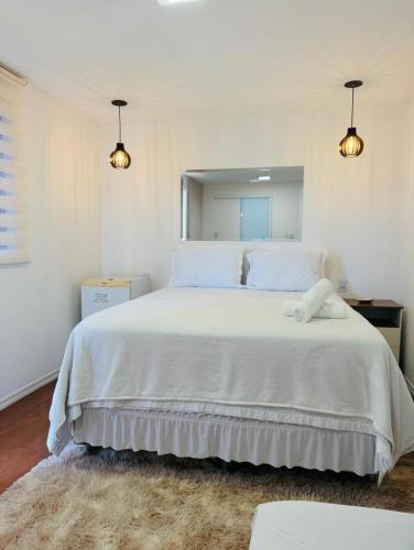 a bedroom with a large white bed with a mirror at Bangalô Miraflores in Chapada dos Guimarães