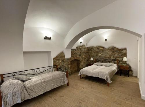 a bedroom with two beds and a stone wall at Princo Apartments in Hunedoara