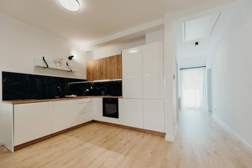a kitchen with white cabinets and a wooden floor at Apartamenty Jasionka Lotnisko in Rudna Mała