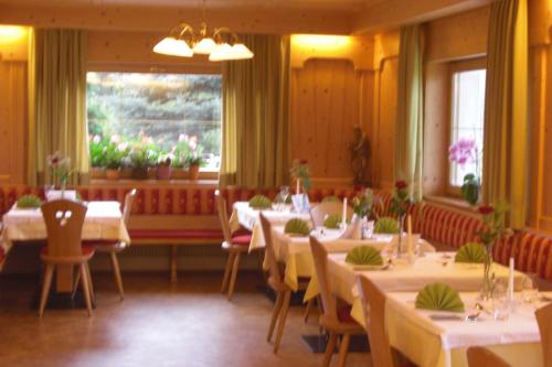 a dining room with white tables and chairs and a window at Hotel Wieslhof in Collepietra