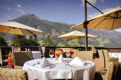 a table with wine glasses and umbrellas on a patio at Hotel Goldried in Matrei in Osttirol