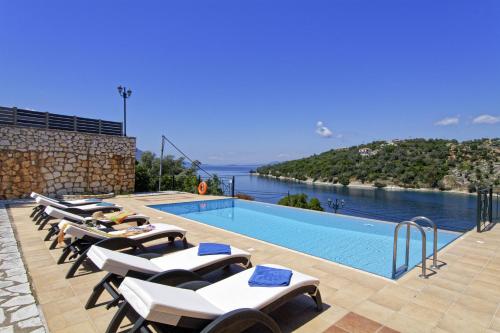 Una fila de tumbonas junto a una piscina. en Villa Constantina Meganisi, en Meganisi
