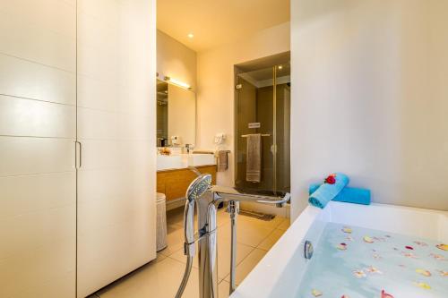 a bathroom with a tub and a sink at Cap Ouest by Horizon Holidays in Flic-en-Flac
