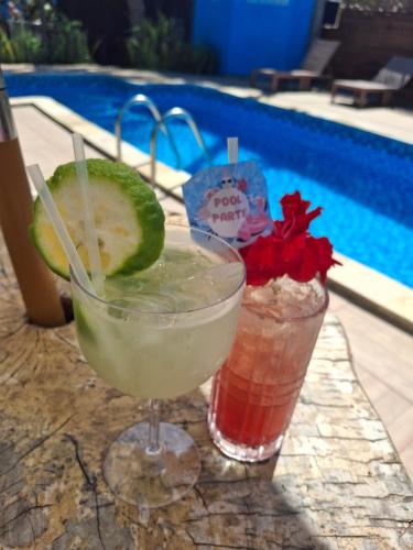 two drinks sitting on a table next to a pool at Pousada Manga Azul in Barra de Camaratuba