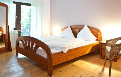 Schlafzimmer mit einem Holzbett mit weißer Bettwäsche und Kissen in der Unterkunft Ferienwohnungen Grimm in Nennslingen