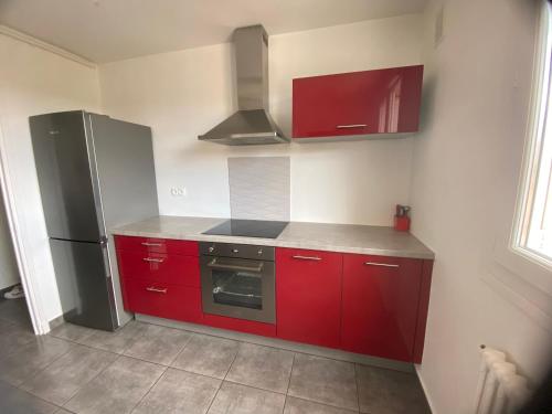 une cuisine avec des armoires rouges et un réfrigérateur dans l'établissement Bel appartement 2 chambres, proche centre ville - parking, à Vals-près-le-Puy