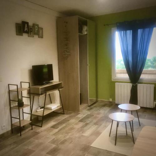 une pièce avec une télévision, deux tables et une fenêtre dans l'établissement location studio Presqu'ile de Giens, à Hyères