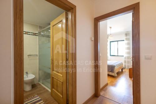 una habitación con ducha y WC y un dormitorio en Apartamento Ouriço by ACasaDasCasas, en Ericeira