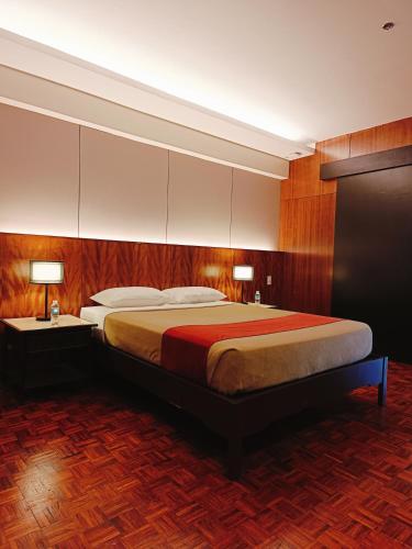 a bedroom with a large bed with two tables and two lamps at Tropicana Suites in Manila
