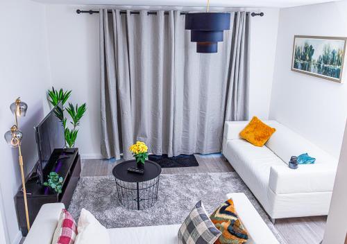 a living room with a white couch and a table at Monea Retreat a Modern 2bedroom and 2 bathroom apartment in Coventry in Coventry