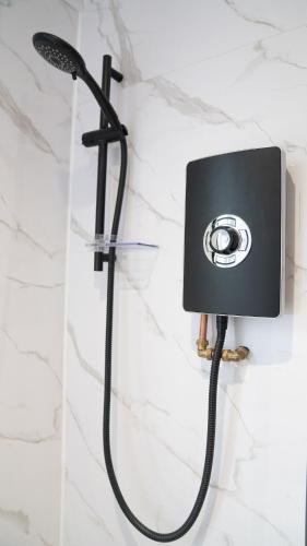 a shower with a hose attached to a wall at Luxury Stay by City Centre Etihad and COOP Live in Manchester