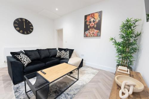a living room with a black couch and a clock at Luxury Stay by City Centre Etihad and COOP Live in Manchester