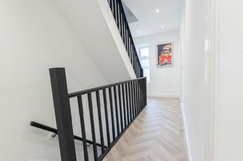 a staircase with black railings in a white hallway at Luxury Stay by City Centre Etihad and COOP Live in Manchester