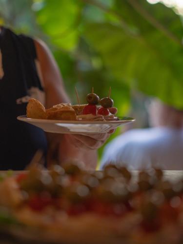 a woman holding a plate of food on top of a pizza at Casa de hóspedes Balibar Cumbuco in Cumbuco