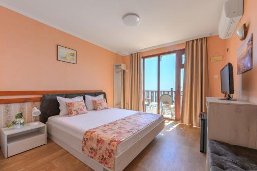 a bedroom with a bed and a tv and a balcony at Morski Briag Hotel in Golden Sands