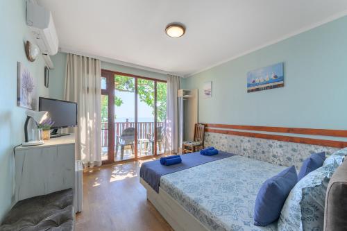 a bedroom with a bed and a television and a balcony at Morski Briag Hotel in Golden Sands