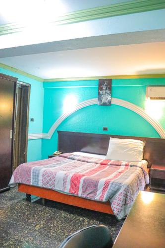 a bedroom with a bed with a blue wall at Royal Hôtel in Brazzaville