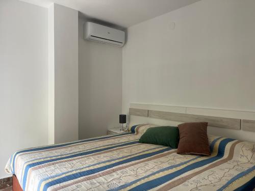 a bedroom with a bed with a striped blanket at Apartamento en Almuñécar con piscina comunitaria in Almuñécar