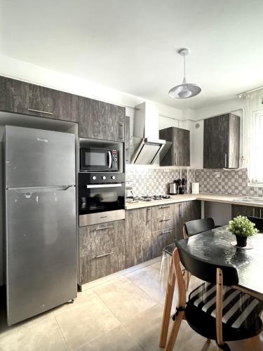 a kitchen with a stainless steel refrigerator and a table at Modern and family-friendly apartment in Birkhadem in Birkhadem