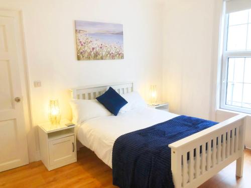 a bedroom with a white bed with a blue blanket at 10 Seconds to Main Street! in Wexford