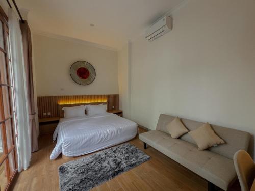 a bedroom with a bed and a couch at Gee Villas Yogyakarta in Ngingas