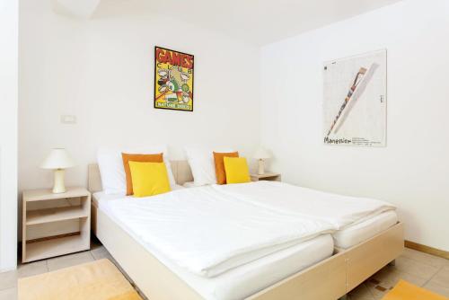 um quarto com uma cama com lençóis brancos e almofadas amarelas em Apartments Kump em Rovinj