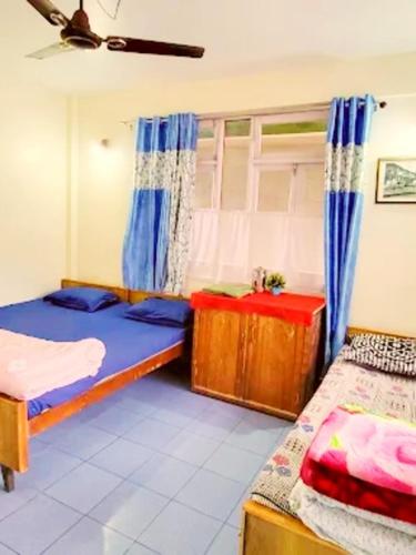 a bedroom with two beds and a table in it at Hotel Shalimar in Kalimpong