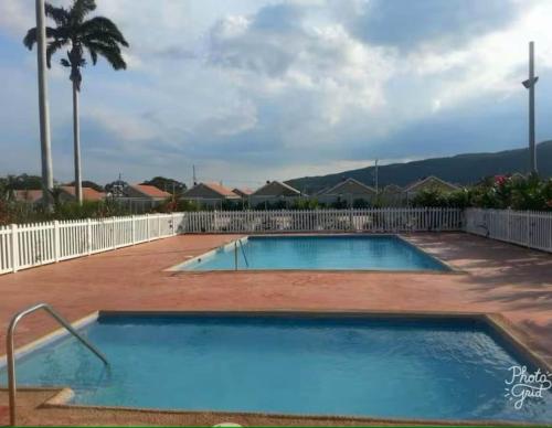 a large blue swimming pool next to a white fence at KOSC Retreat at Caymanas Estate in Portmore