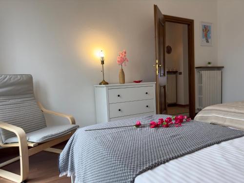a bedroom with a bed and a chair and flowers on a table at Tavernola Suites - A due passi dal Traghetto in Como