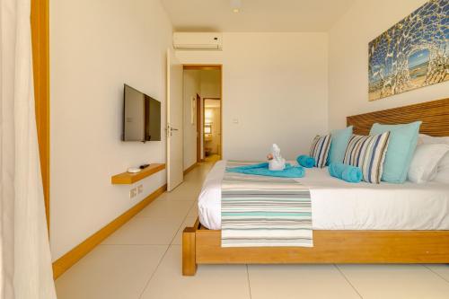 a bedroom with a large bed with blue pillows at Cap Ouest by Horizon Holidays in Flic-en-Flac