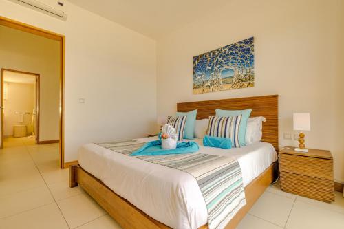 a bedroom with a large bed with blue pillows at Cap Ouest by Horizon Holidays in Flic-en-Flac