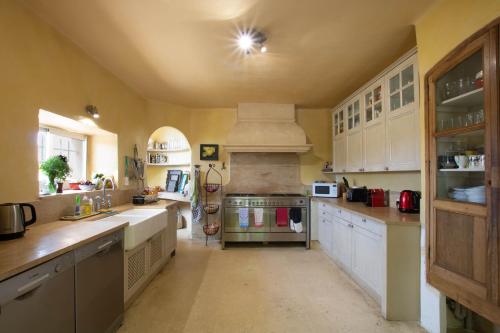 une grande cuisine avec des placards blancs et une cuisinière dans l'établissement Le Château de la Baude, à Villedieu