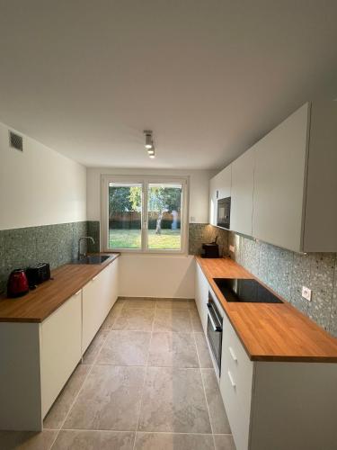 une grande cuisine avec des armoires blanches et une fenêtre dans l'établissement Maison Cosy à Chartres, à Chartres