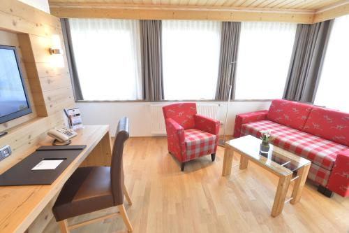 a living room with a red couch and a table at Best Western Plus Hotel Alpenhof in Oberstdorf