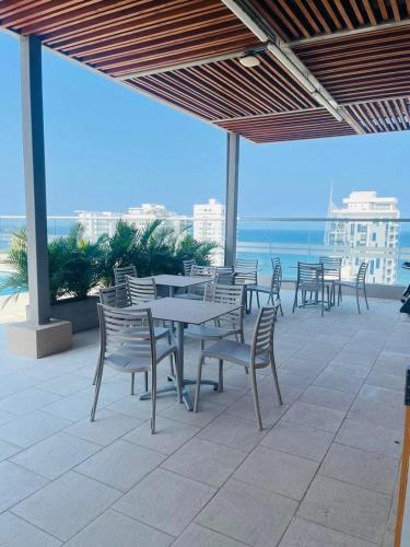 a patio with tables and chairs and the ocean at Salguero Suites - Playa Salguero - By INMOBILIARIA VS in Santa Marta