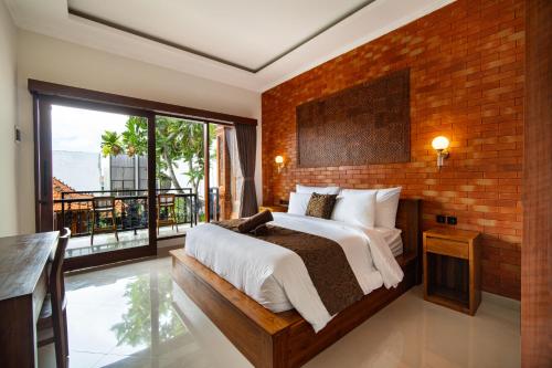 a bedroom with a large bed and a brick wall at Pendopo Canggu Village in Canggu