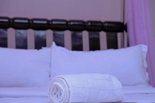 a white towel sitting on top of a bed with pillows at Primland Hotel Buyala in Buloba