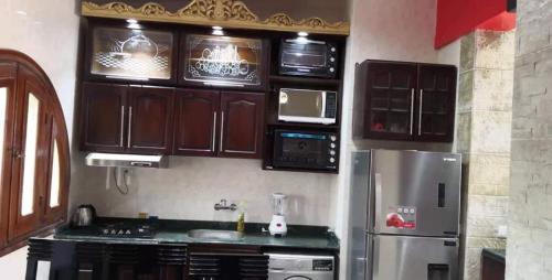 una cucina con mobili in legno e un frigorifero in acciaio inossidabile di Four bed rooms chalet in marina 7 a El Alamein