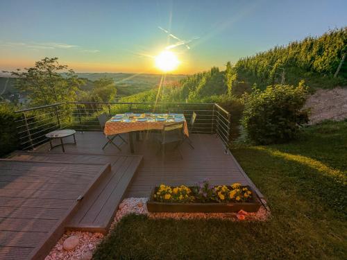 a wooden deck with a table and flowers on it at Heavenly Abode - Barbaresco in Barbaresco