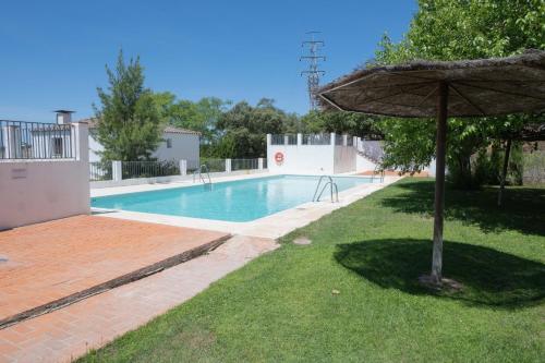 una piscina con sombrilla junto a un patio en La Casita de San Gonzalo, en Higuera de la Sierra
