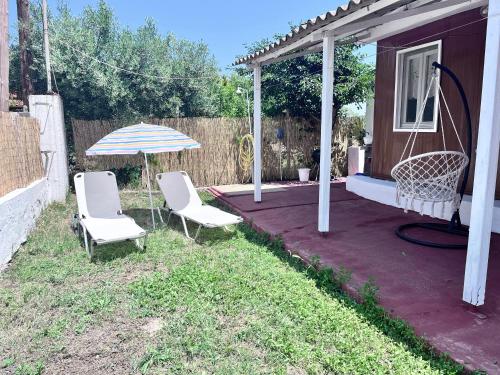 a patio with two chairs and an umbrella at The Beach house in Platanitis Rodopis