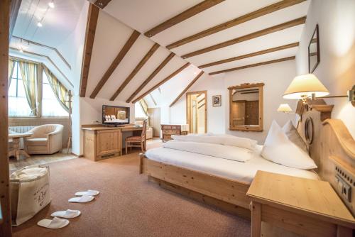ein Schlafzimmer mit einem großen Bett und einem Schreibtisch in der Unterkunft Die Post am Ortler in Sulden