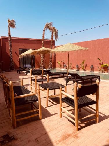 a group of tables and chairs with umbrellas on a patio at Modern oasis near Palmeraie - Dar Tal in Douar Oulad Ali