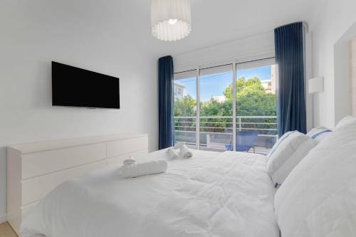 - une chambre blanche avec un grand lit blanc et une télévision à écran plat dans l'établissement 2-bedroom Royal Beach, à 2minutes de la plage, à Cannes