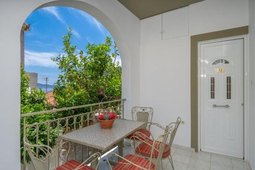 a patio with a table and chairs on a balcony at MAKIS VILLAGE-APARTMENTS in Ayia Evfimia