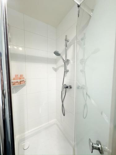 une salle de bain avec une douche avec une porte vitrée dans l'établissement L Écrin de Neuilly - La Défense & Champs Elysées 10 min away, à Neuilly-sur-Seine