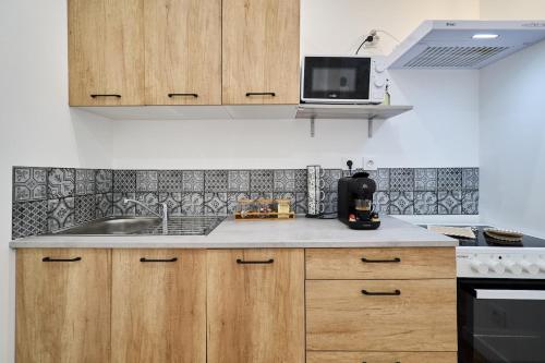 une cuisine avec des armoires en bois et un évier dans l'établissement Summer - Centre-Ville Gare - Spacieux - Netflix, à Reims